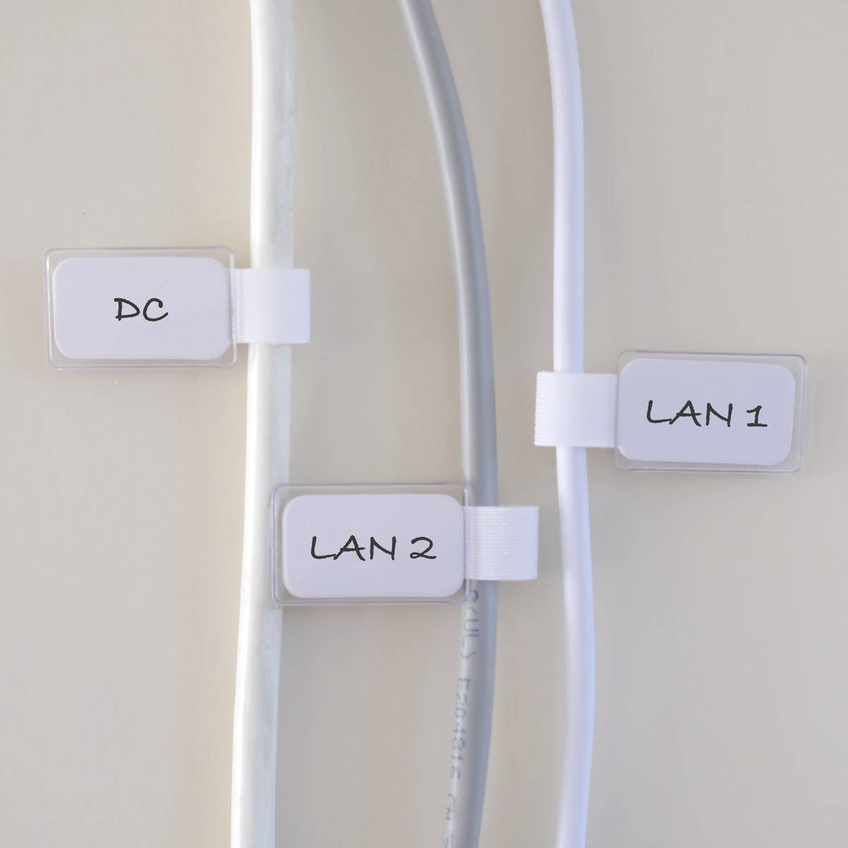 Trois câbles sur un mur, étiquetés 'DC', 'LAN 2' et 'LAN 1'.