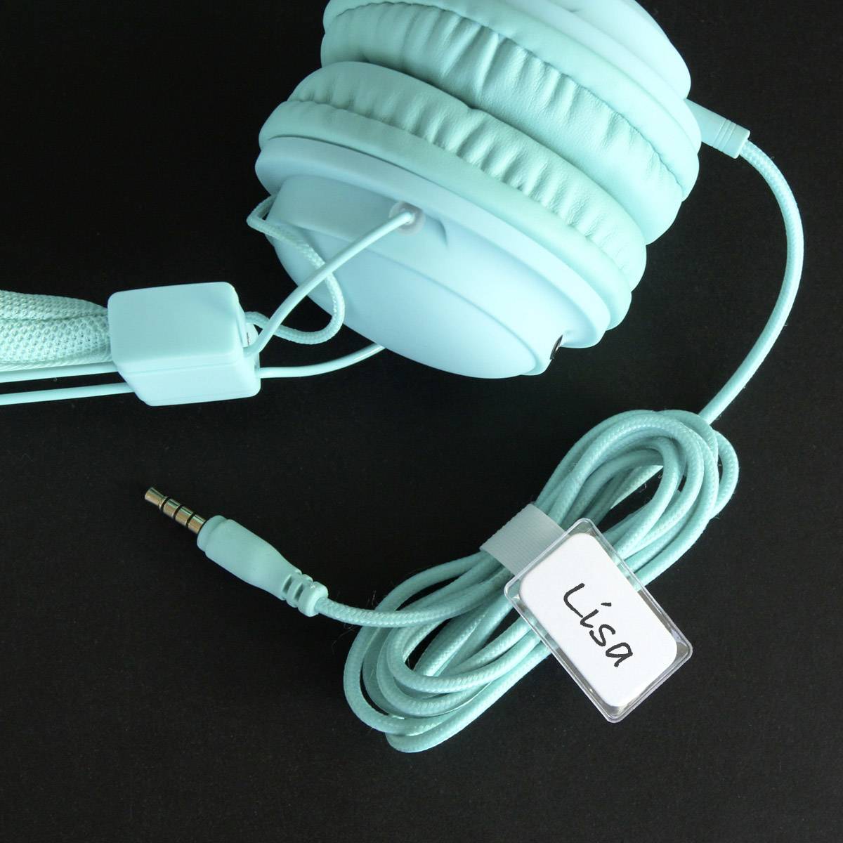 Écouteurs turquoise avec un câble sur lequel est attachée une étiquette blanche portant le nom 'Lisa', posée sur un fond noir.