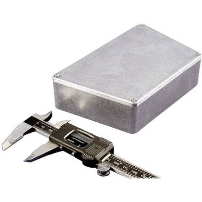 Un calibre métallique est posé à côté d'un boîtier rectangulaire métallique sur une surface blanche.