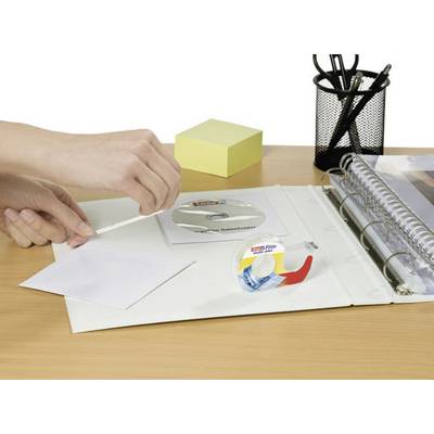 Une personne appose un ruban adhésif sur une enveloppe posée sur un bureau. À côté se trouvent un bloc-notes, des stylos et un classeur.