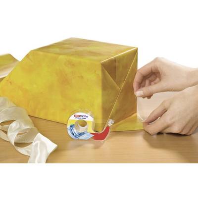 Une personne emballe un cadeau avec du papier jaune et du ruban adhésif. Un nœud et un rouleau de ruban adhésif sont posés sur la table.