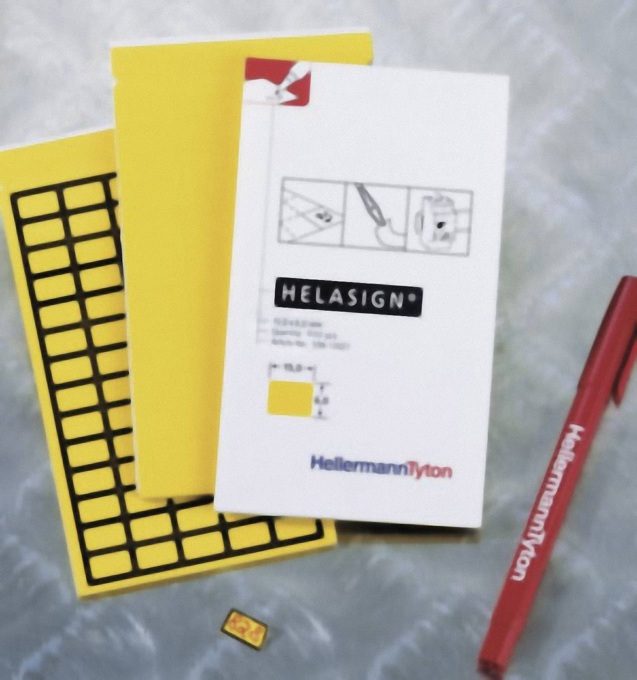 Deux blocs-notes jaunes, un cahier blanc portant l'inscription 'Helasign', un stylo HellermannTyton et une petite étiquette jaune.