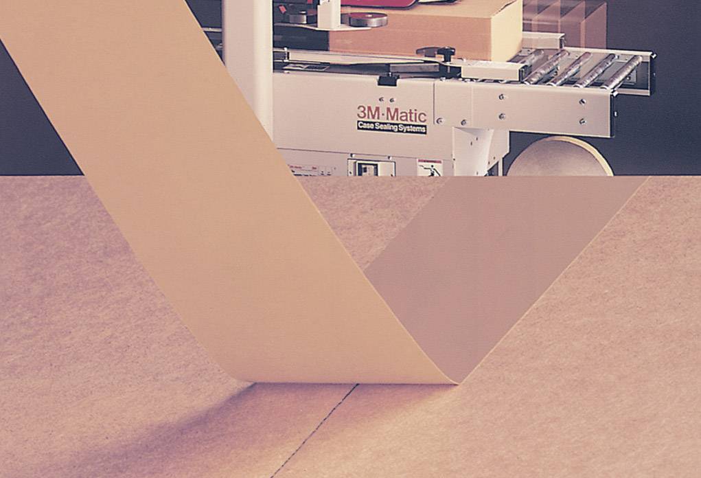 Une machine ferme des cartons avec du ruban adhésif.