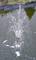 Fontaine dans l'étang projetant des jets d'eau dans les airs. Arrière-plan avec surface de l'eau, écume et herbe sur la rive.