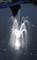 Jeu d'eau dans un bassin avec une fontaine à jets, éclairé par le dessous, créant des arcs d'eau lumineux dans un environnement sombre.