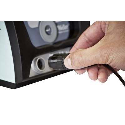 Une main insère une fiche de câble dans une prise sur un appareil électrique.