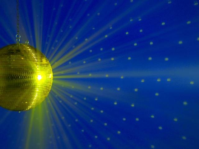 Un boule disco dorée reflète des points de lumière sur un mur bleu, créant une atmosphère de fête.