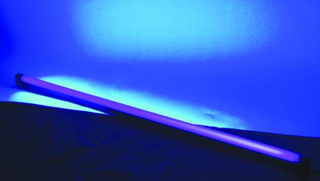 Une baguette lumineuse bleue est posée diagonalement sur une surface, devant un arrière-plan éclairé en bleu.