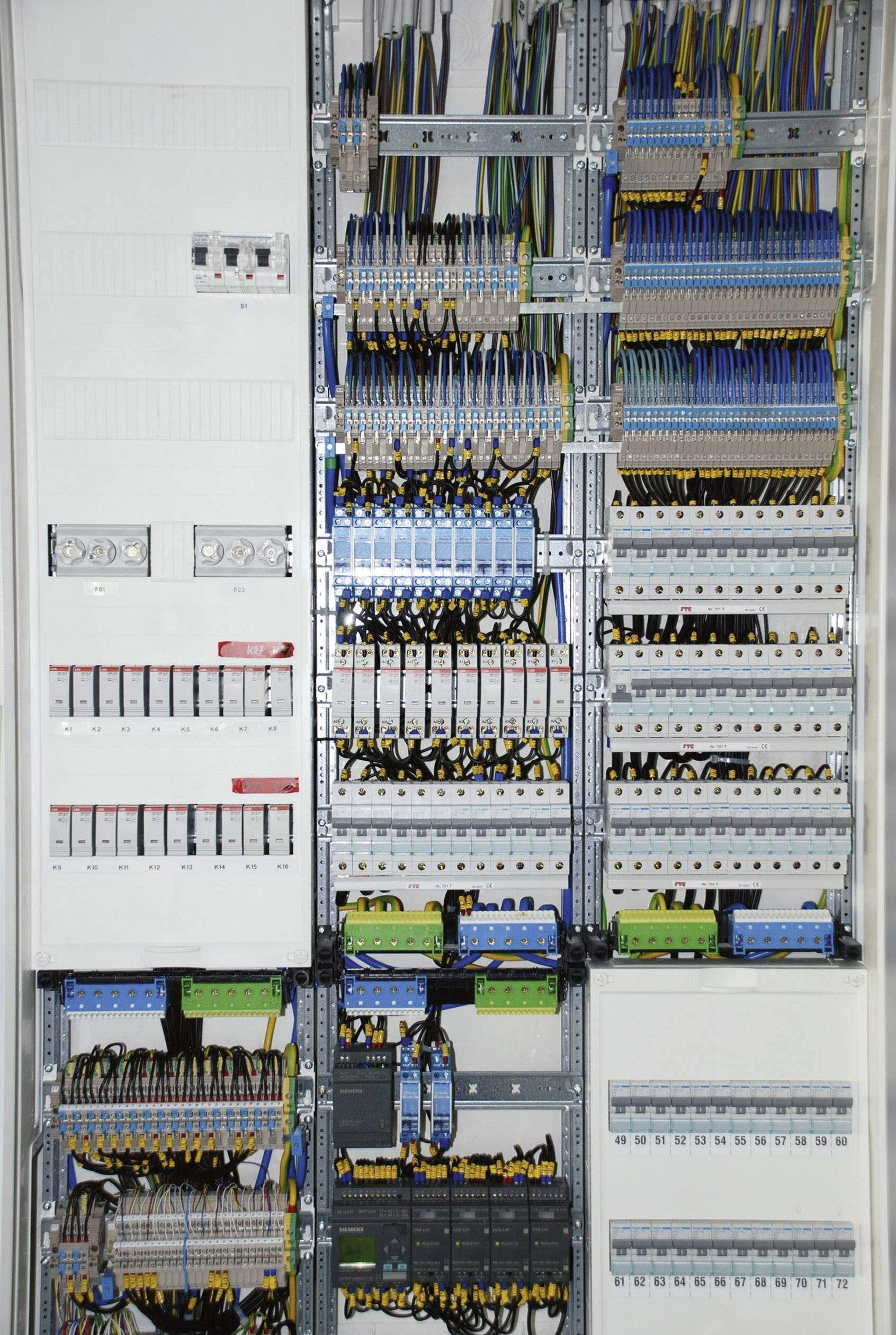 'Armoire électrique avec de multiples câblages et fusibles, montrant une installation électrique complexe et ses points de connexion.'