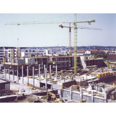 Un chantier de construction avec de grandes grues et un bâtiment multi-étages en cours de construction. Des ouvriers et des matériaux sont visibles.