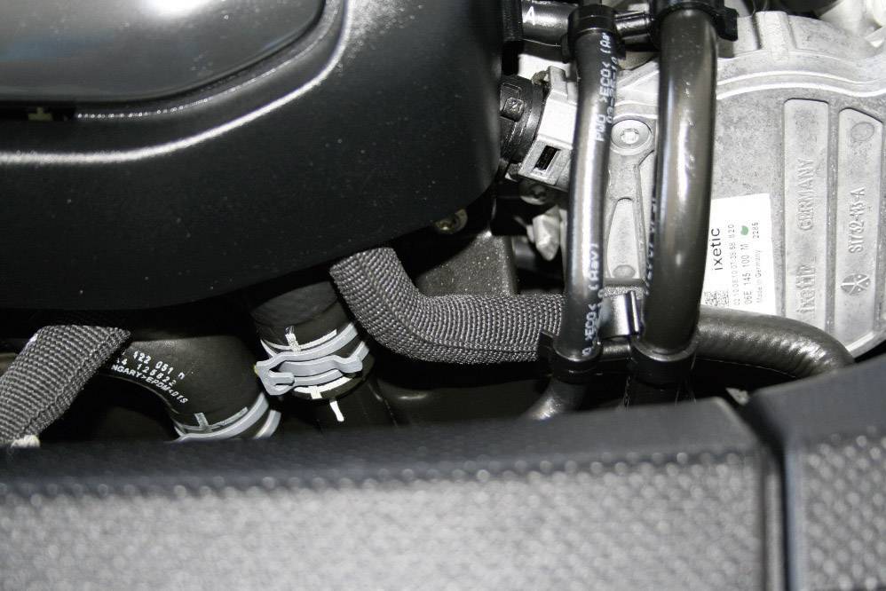 Gros plan d'un composant moteur automobile avec plusieurs tuyaux et éléments métalliques. Aucun texte ou marquage spécifique n'est visible.