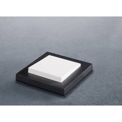 Un objet plat, carré et blanc repose sur une base carrée plus grande, noire, sur un fond gris.