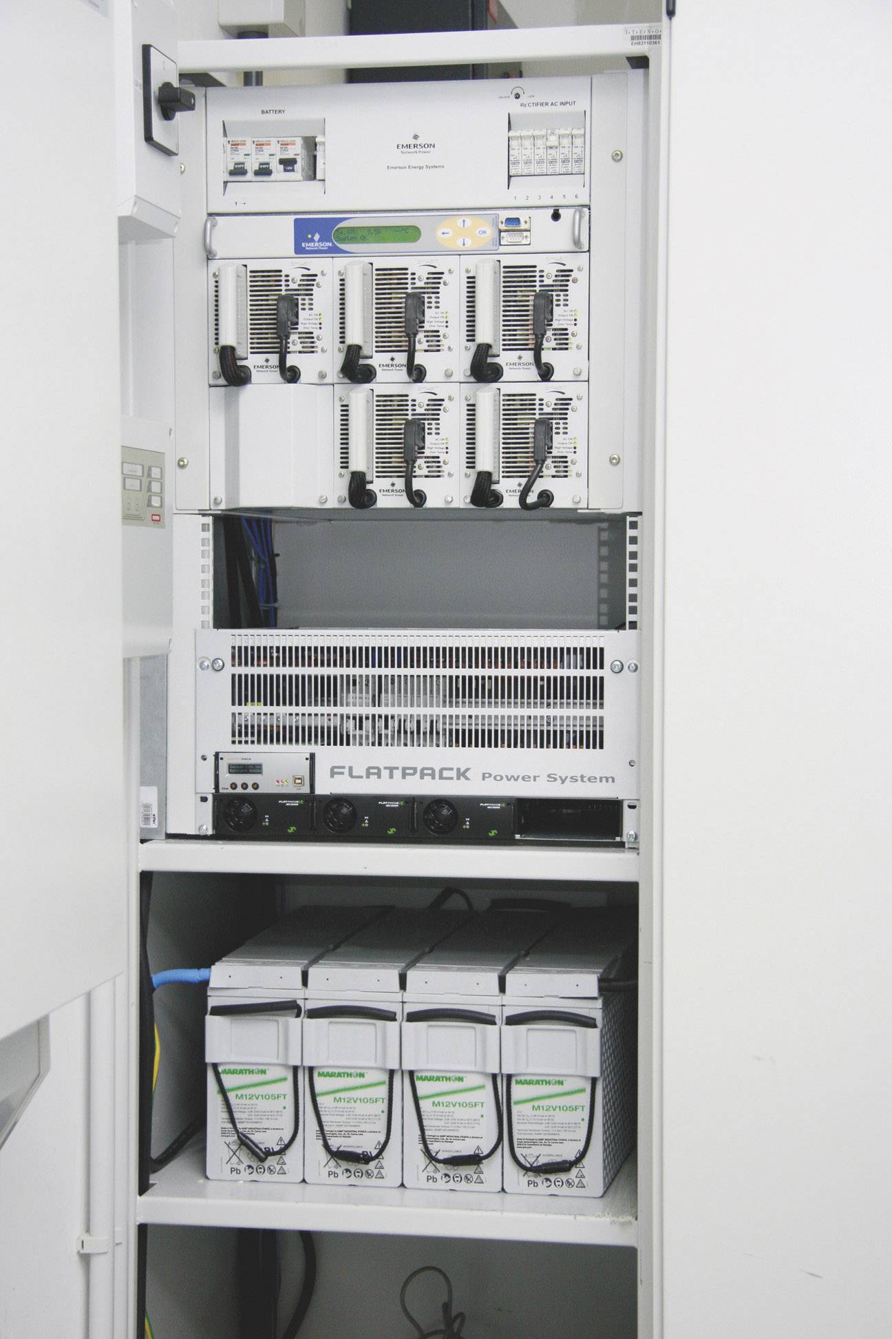 Un baie serveur ouverte contenant plusieurs équipements techniques tels qu'un routeur, des cartes réseau et des unités d'alimentation électrique.