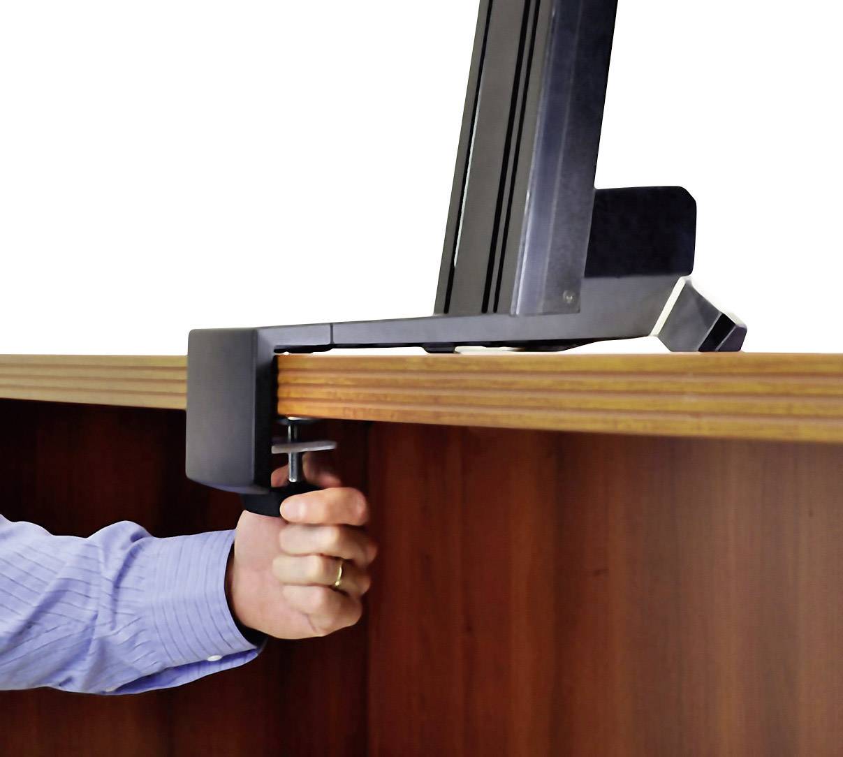 Une main fixe un support de moniteur à une table en bois à l'aide d'une pince.