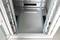 Armoire serveur vide et ouverte en métal. Elle présente des traverses latérales et inférieures, prête à accueillir du matériel serveur.
