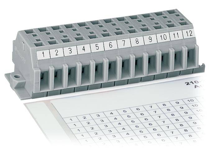 Un bloc de bornes électriques gris avec des connexions numérotées de 1 à 12 est posé sur une feuille imprimée de chiffres.
