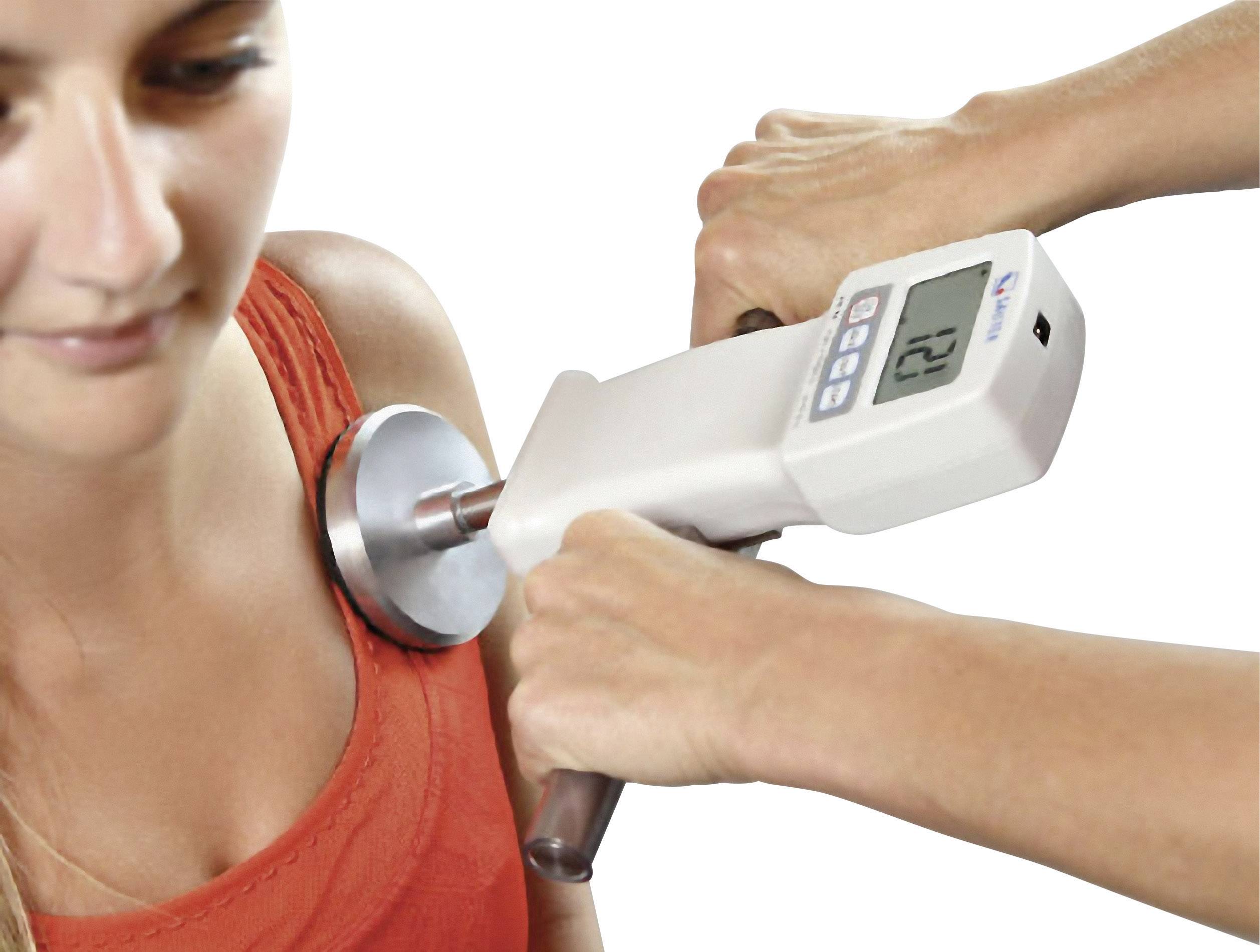Une personne porte un haut orange. Un appareil est pressé contre son épaule pour effectuer une mesure.