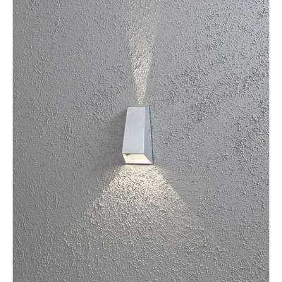 Un applique murale moderne en métal projette des rayons lumineux vers le haut et vers le bas sur un mur gris texturé.