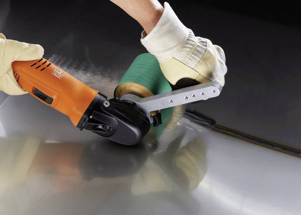 Une personne utilise un outil électrique rotatif avec un embout vert pour polir une surface métallique.