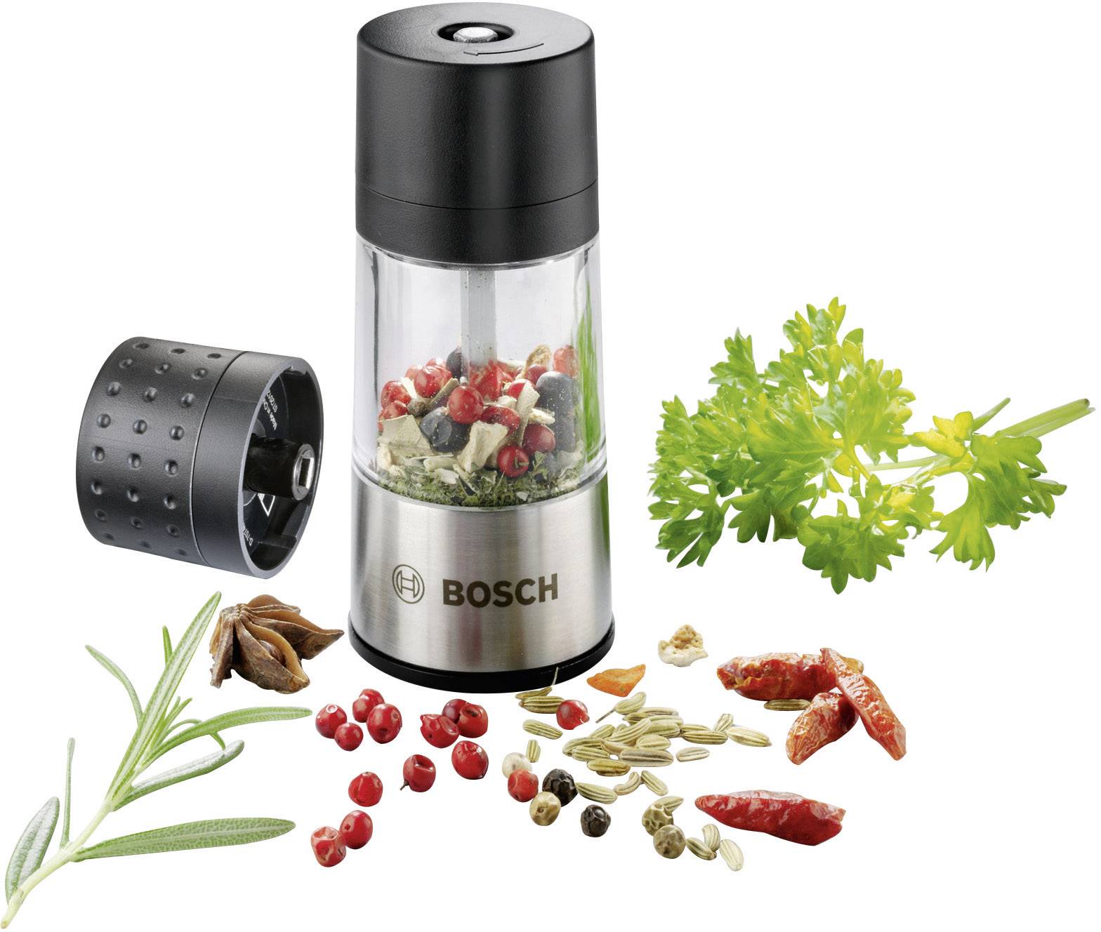 Moulin à épices électrique avec son couvercle retiré, rempli d'épices colorées. À côté, des herbes fraîches et des épices sont dispersées en vrac.