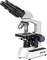 Un microscope blanc et noir avec trois objectifs et un oculaire double. Il est posé sur une table et prêt à être observé.