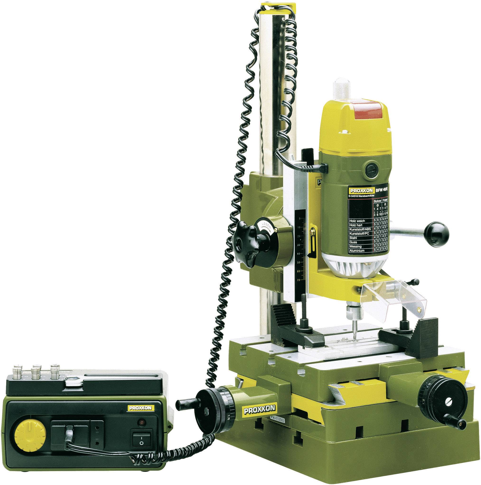 Machine à fraiser verte sur une table, avec un support jaune. À côté, une unité de contrôle électronique noire.