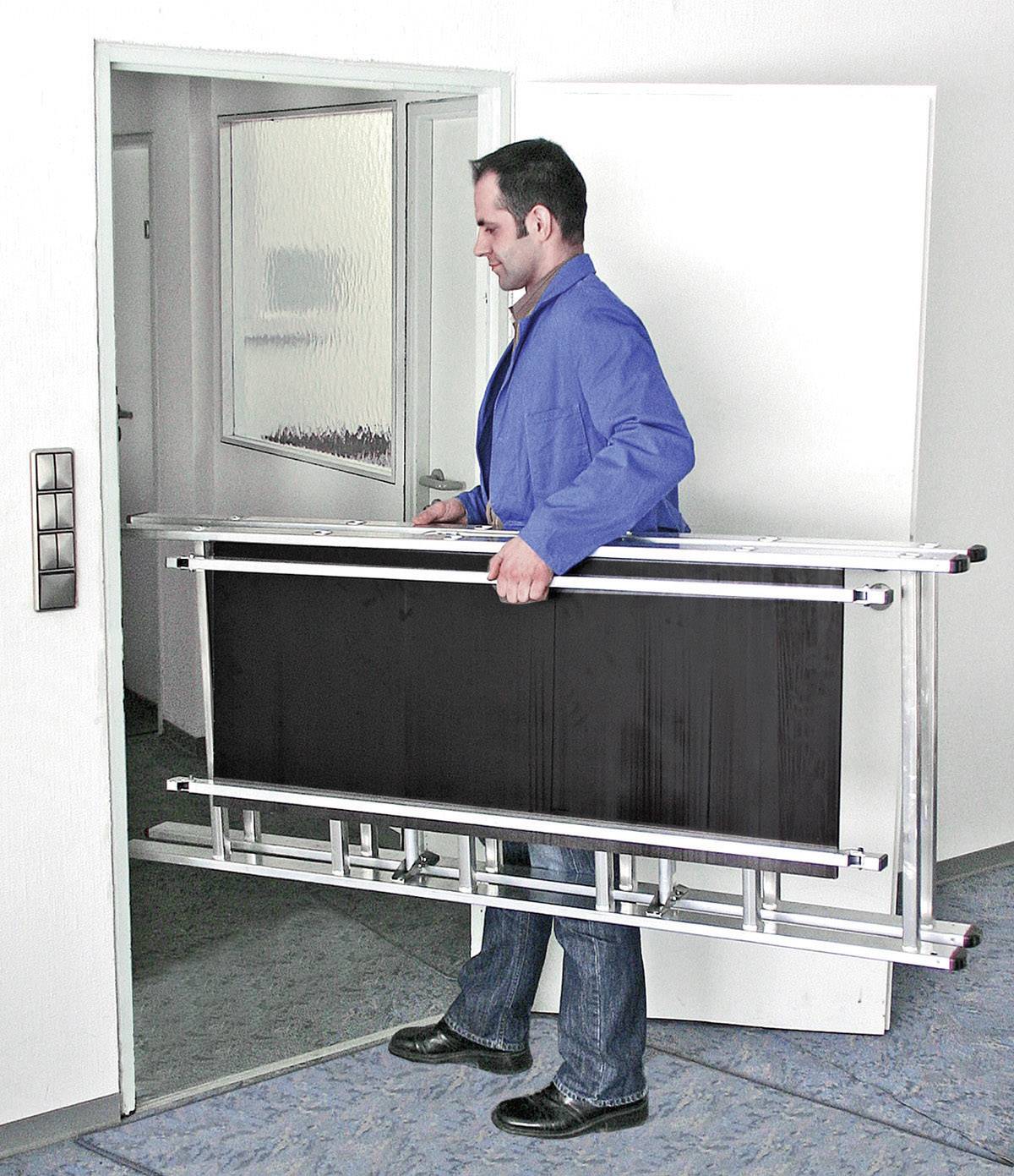 Un homme transporte une échelle pliante à travers une porte ouverte dans un immeuble de bureaux.