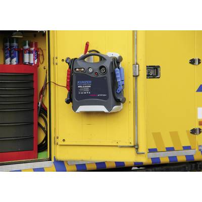 Un véhicule jaune avec un dispositif de démarrage portable à l'extérieur, entouré de divers appareils et câbles.