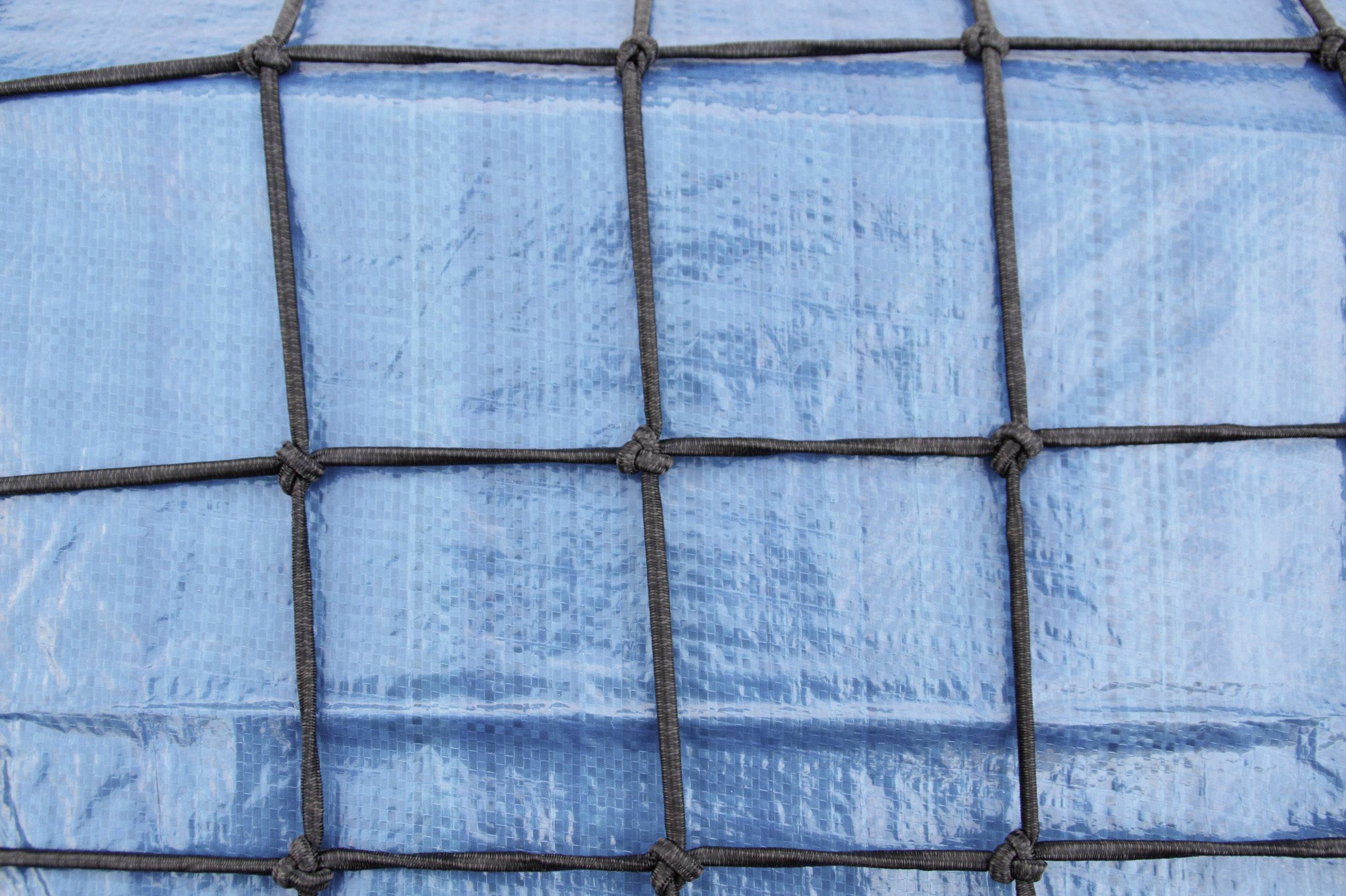 Un colis de transport bleu, sécurisé par un filet noir. Le filet forme un motif quadrillé sur toute la surface.