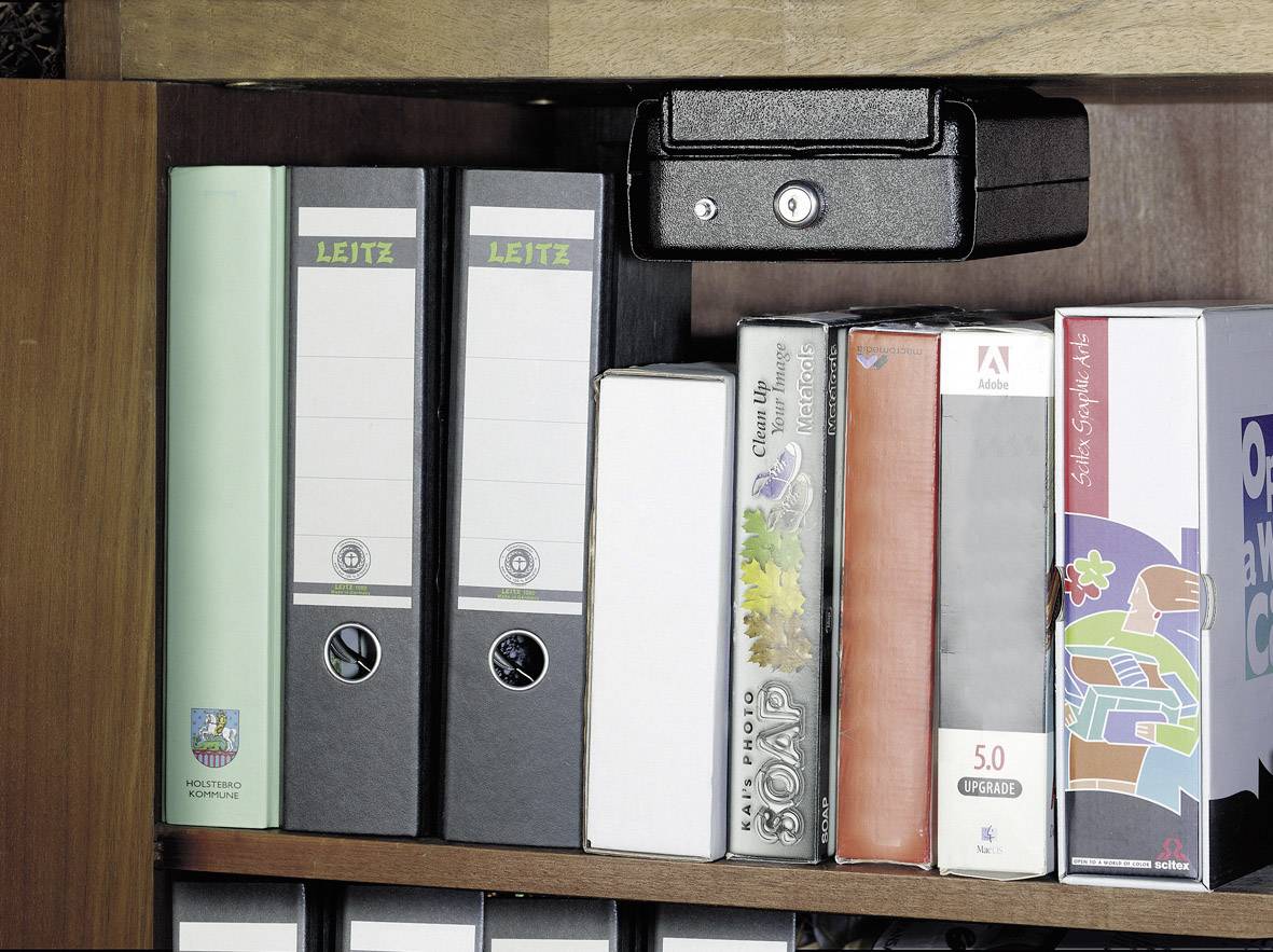 Une étagère avec des classeurs et des boîtes. Deux classeurs portent l'étiquette 'LEITZ'. En haut, une petite cassette noire est posée.