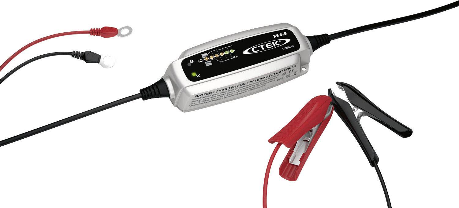 Chargeur de batterie avec voyants et pinces. À gauche, un œillet de câble sur le câble rouge, à droite des pinces en rouge et en noir.