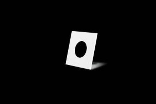 Carte blanche avec un trou rond noir au centre, posée sur un fond noir. Représentation minimaliste.