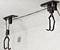Deux supports de vélo noirs fixés au plafond, prêts à suspendre des bicyclettes, avec une corde tendue entre eux.