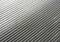 Gros plan d'une surface grise cannelée. Les lignes parallèles traversent diagonalement l'image et créent un motif simple et structuré.