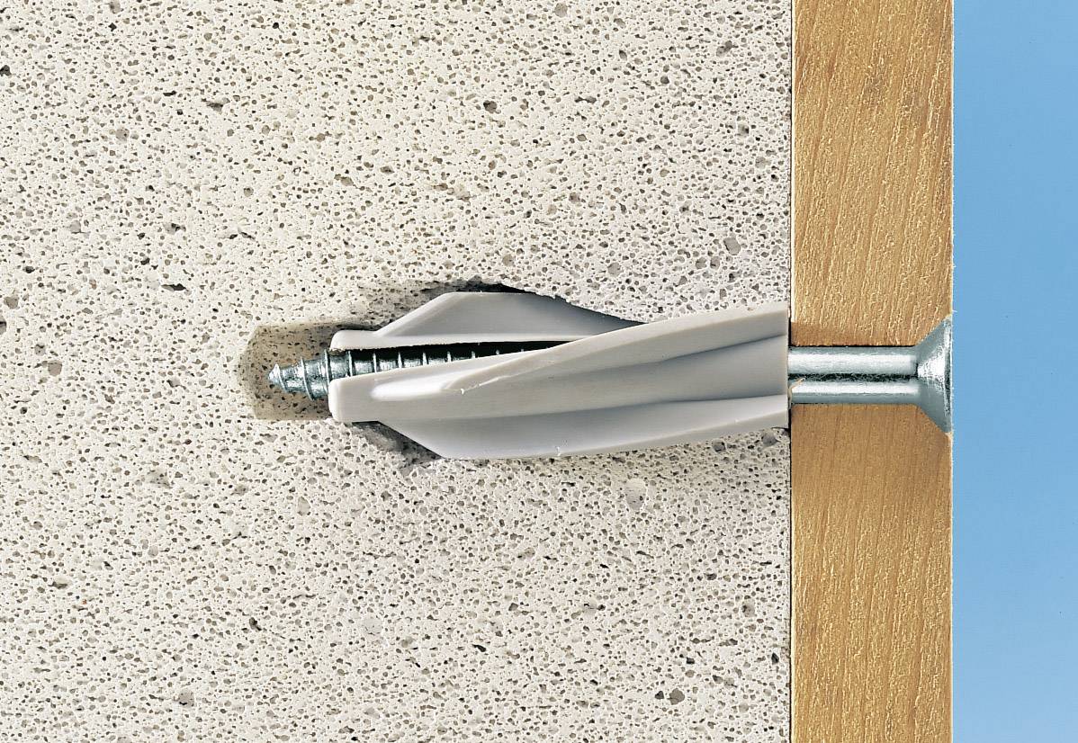 Gros plan d'une cheville dans un mur avec une vis fixée dans du bois. Illustre la fixation dans du béton.