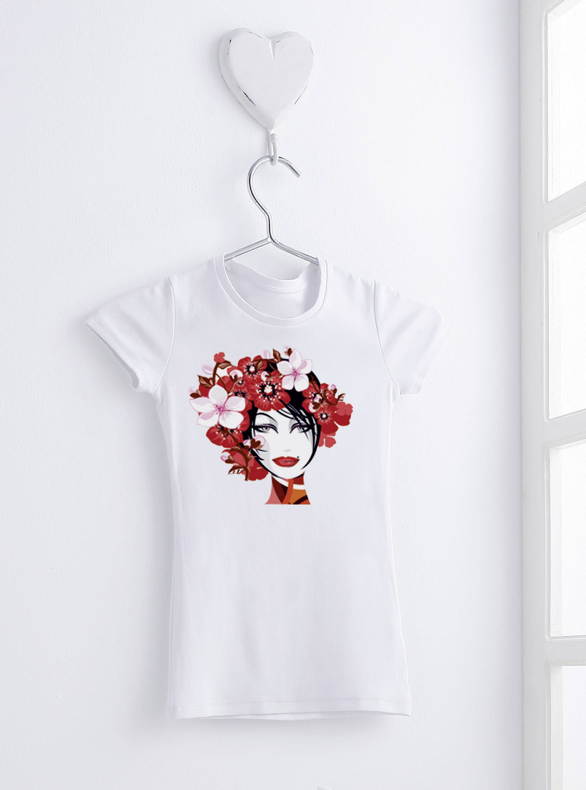 Un t-shirt blanc avec un portrait stylisé d'une femme, orné de fleurs rouges, est accroché à un crochet en forme de cœur sur le mur.