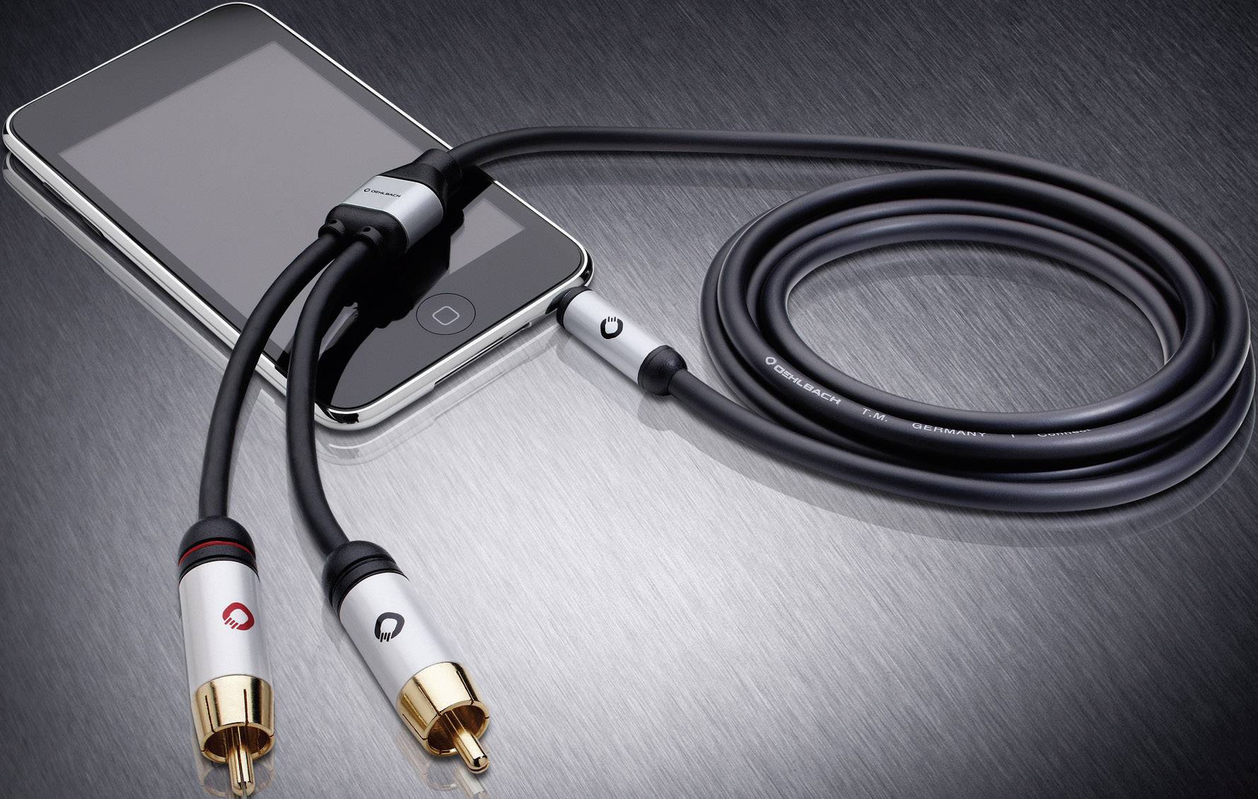 Smartphone connecté à un câble audio avec deux fiches dorées, reposant sur une surface métallique.