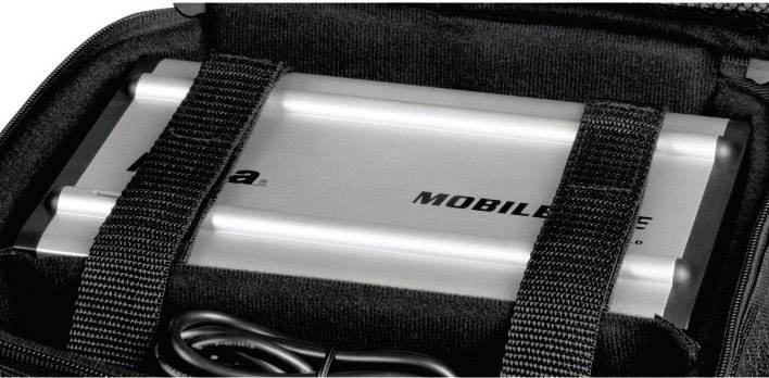 Un chargeur portable argenté est sécurisé dans un étui noir à fermeture velcro, un câble noir repose à côté.