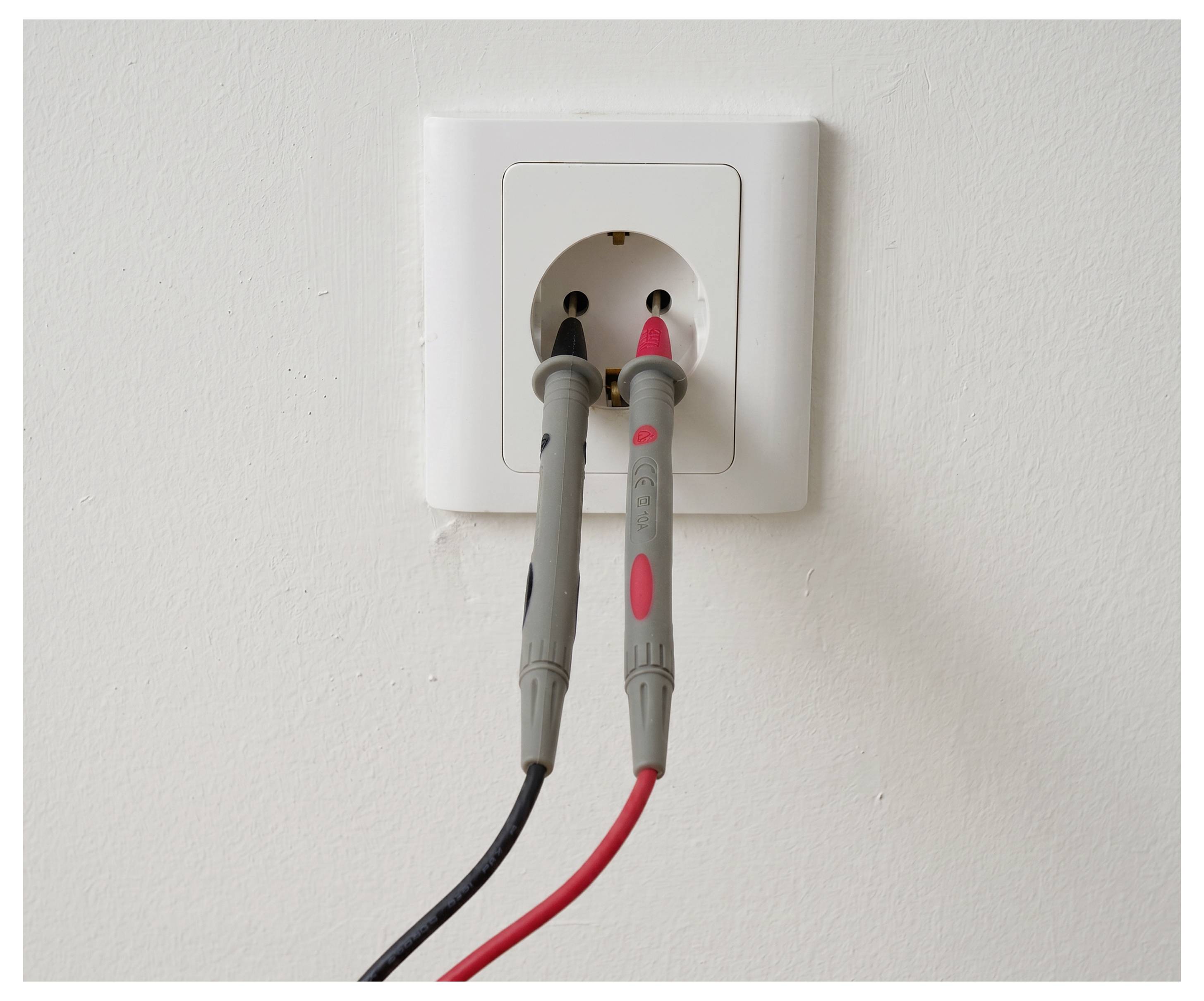 Dvije električne ispitne sonde, jedna crna i jedna crvena, priključene u zidnu utičnicu.
