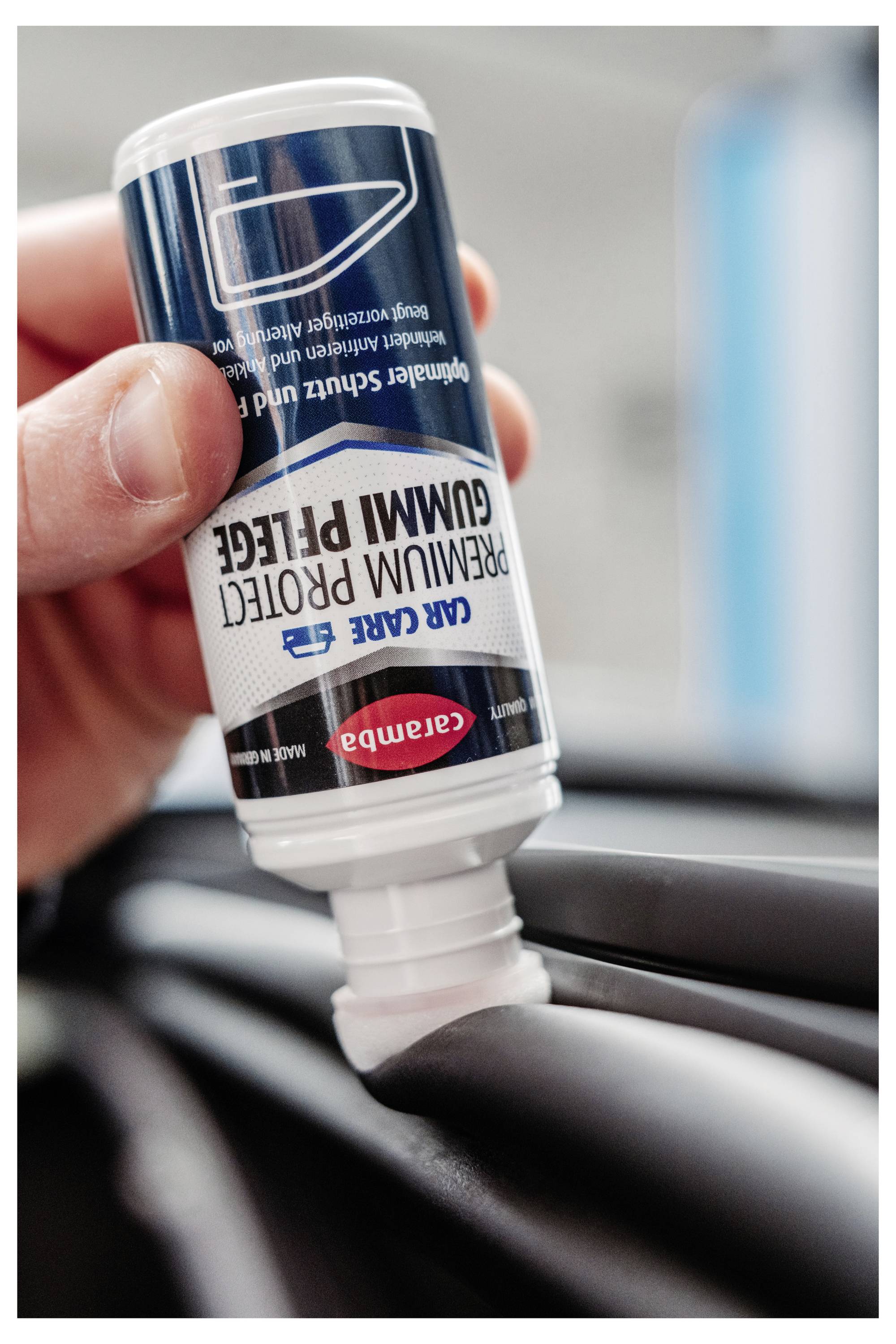 Ruka koja drži preokrenutu flašu CARE GUMM PROTECT kreme dok je nanosi na crnu automobilsku gumu ili traku.