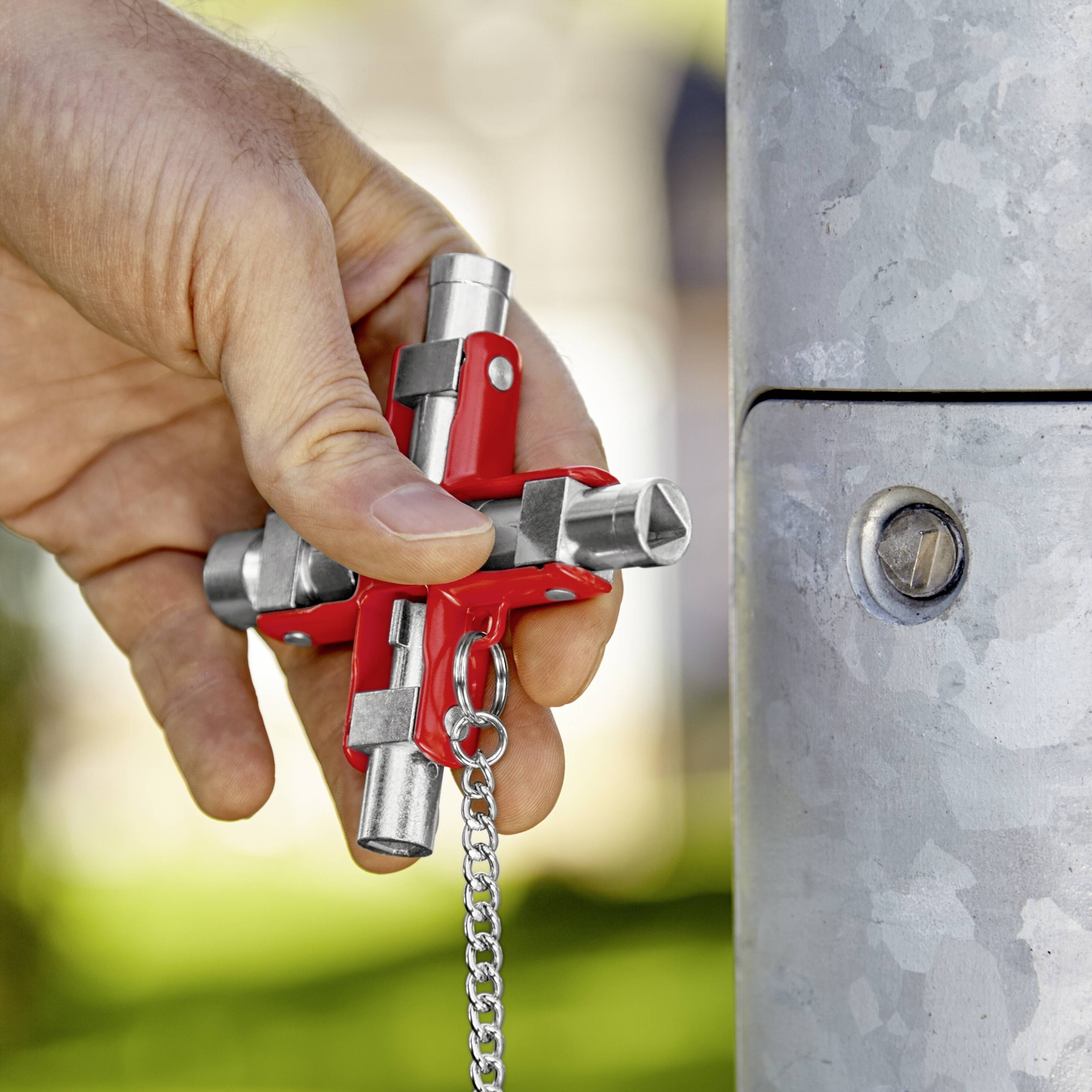 Jedna ruka drži četverokutni ključ koji se koristi za pristup ormarićima električne instalacije na stupovima.