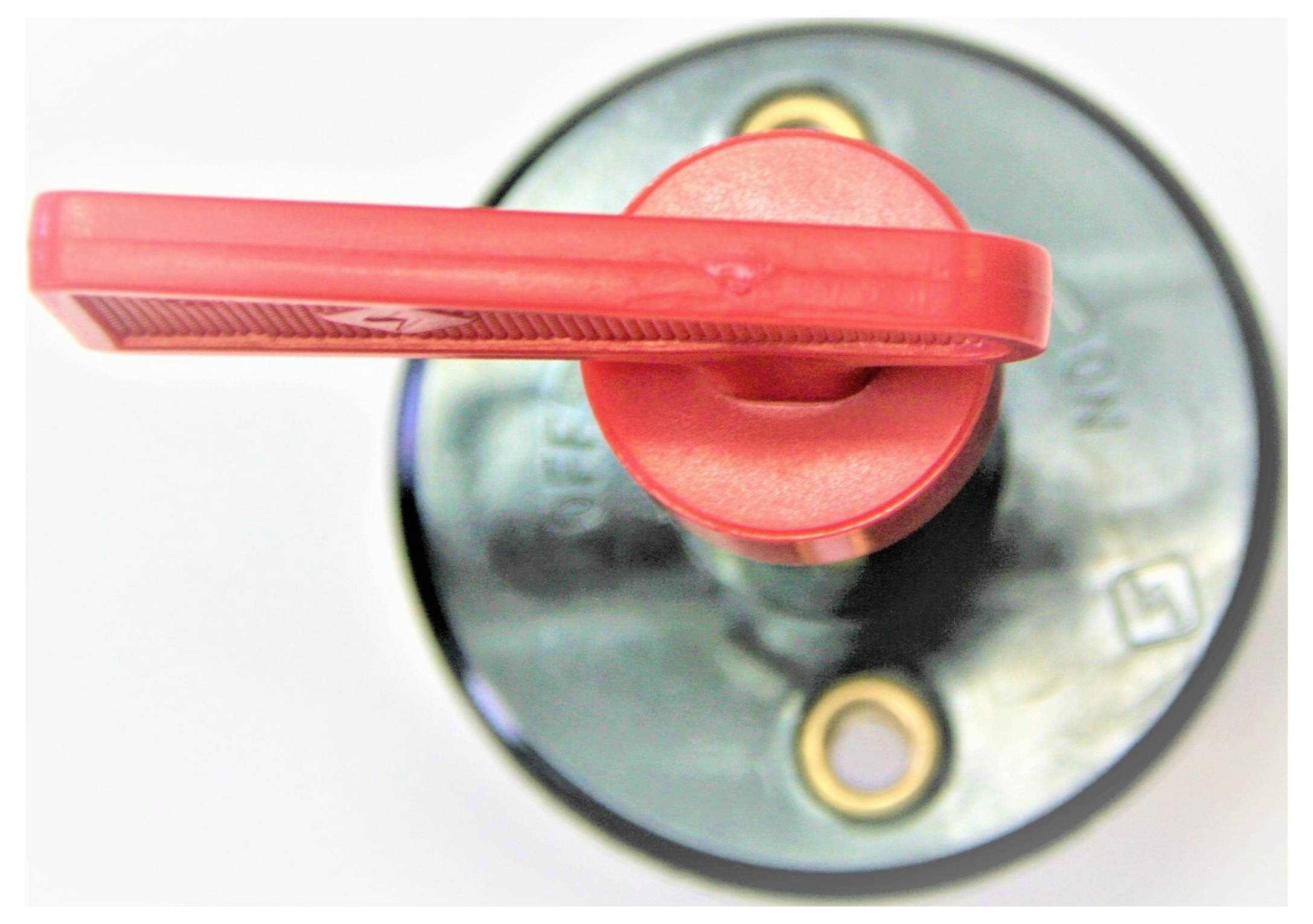 Crvena ručka prekidača postavljena u položaj 'ISKLJUČENO' na okrugloj, metalnoj bazi.