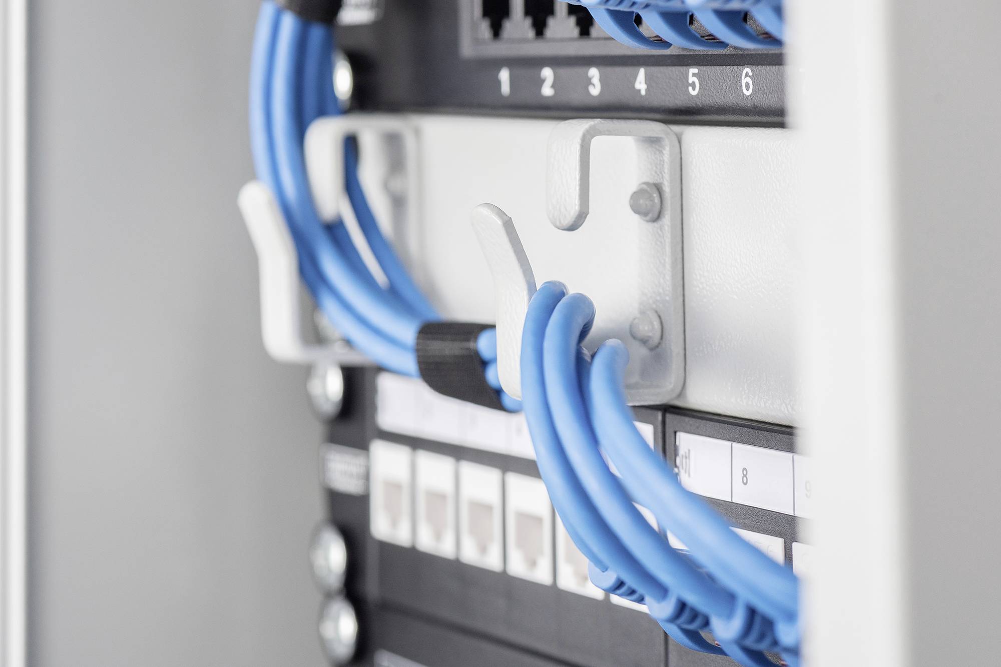 Bliski kadlar poslužiteljskog ormarića s plavim Ethernet kabelima priključenim na mrežne portove.