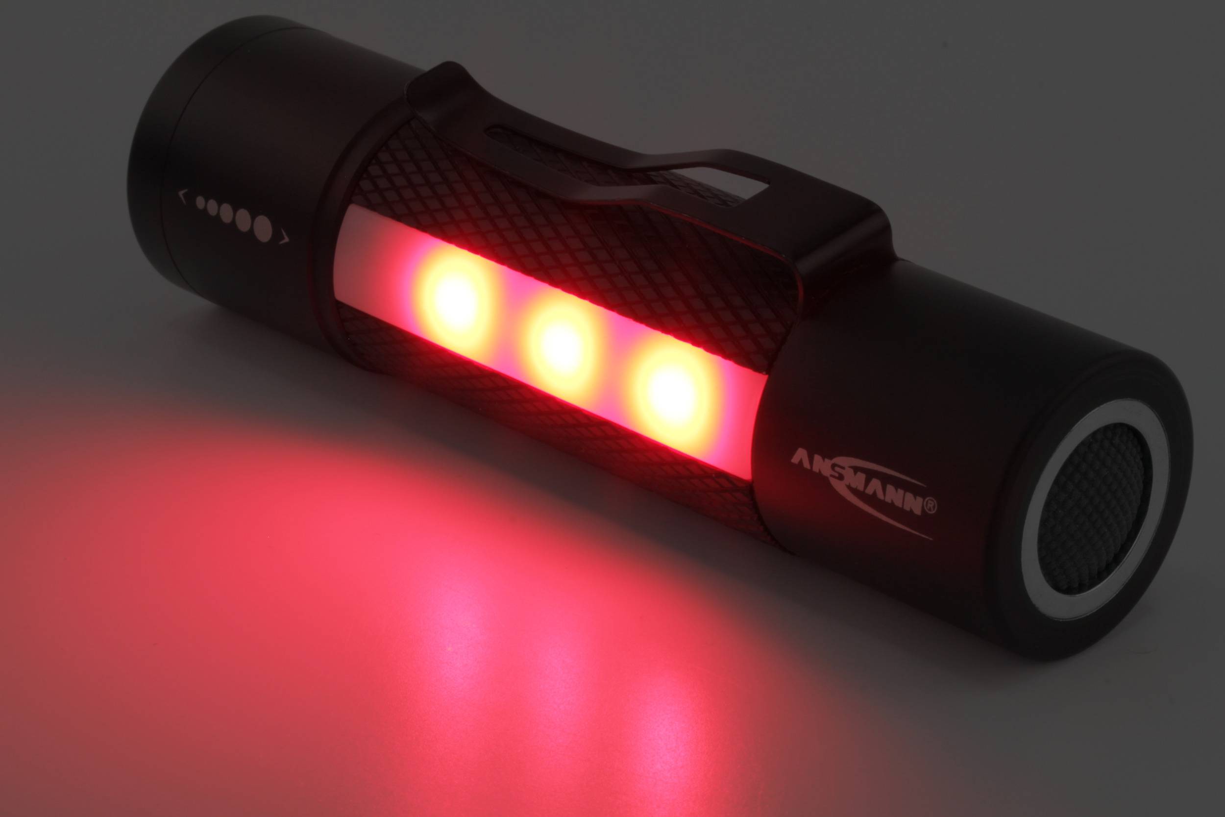 Crna baterijska lampa svijetli s tri crvene LED-ice u mraku.