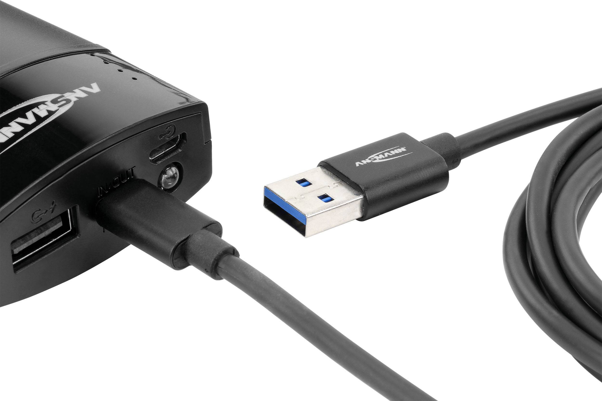 Crni USB kabel priključen je na elektronički uređaj. Kabel završava USB utikačem, prepoznatljivim po plavoj unutarnjoj boji.