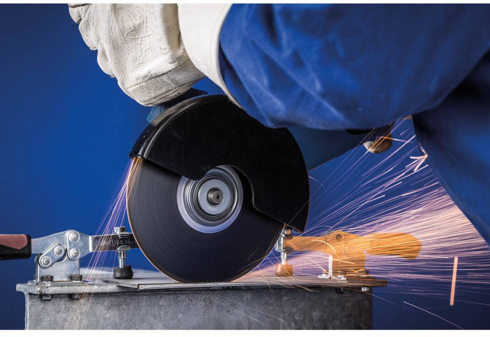 Osoba u zaštitnoj opremi reže metal električnom reznom brusilicama. Varnice lete u zrak.