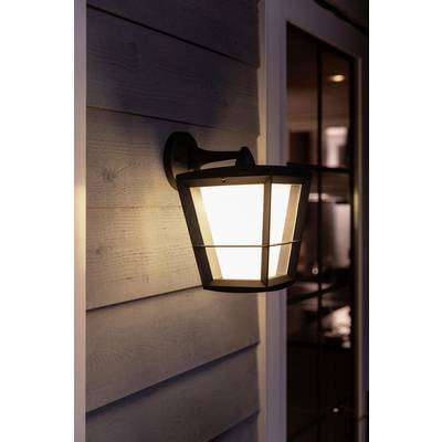 Vanjska lampa osvjetljava verandu u sumrak, postavljena na zidu s drvenom oblogom, pored staklenih vrata.