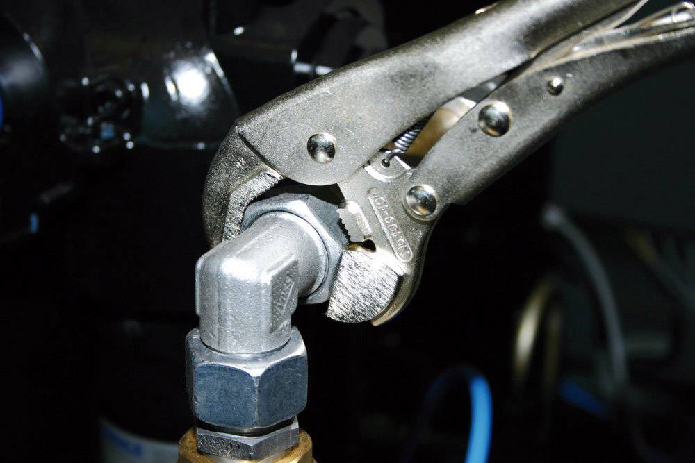 Pumparica hvata pravokutnu metalnu cijev na jednom spoju, okružena industrijskom opremom.