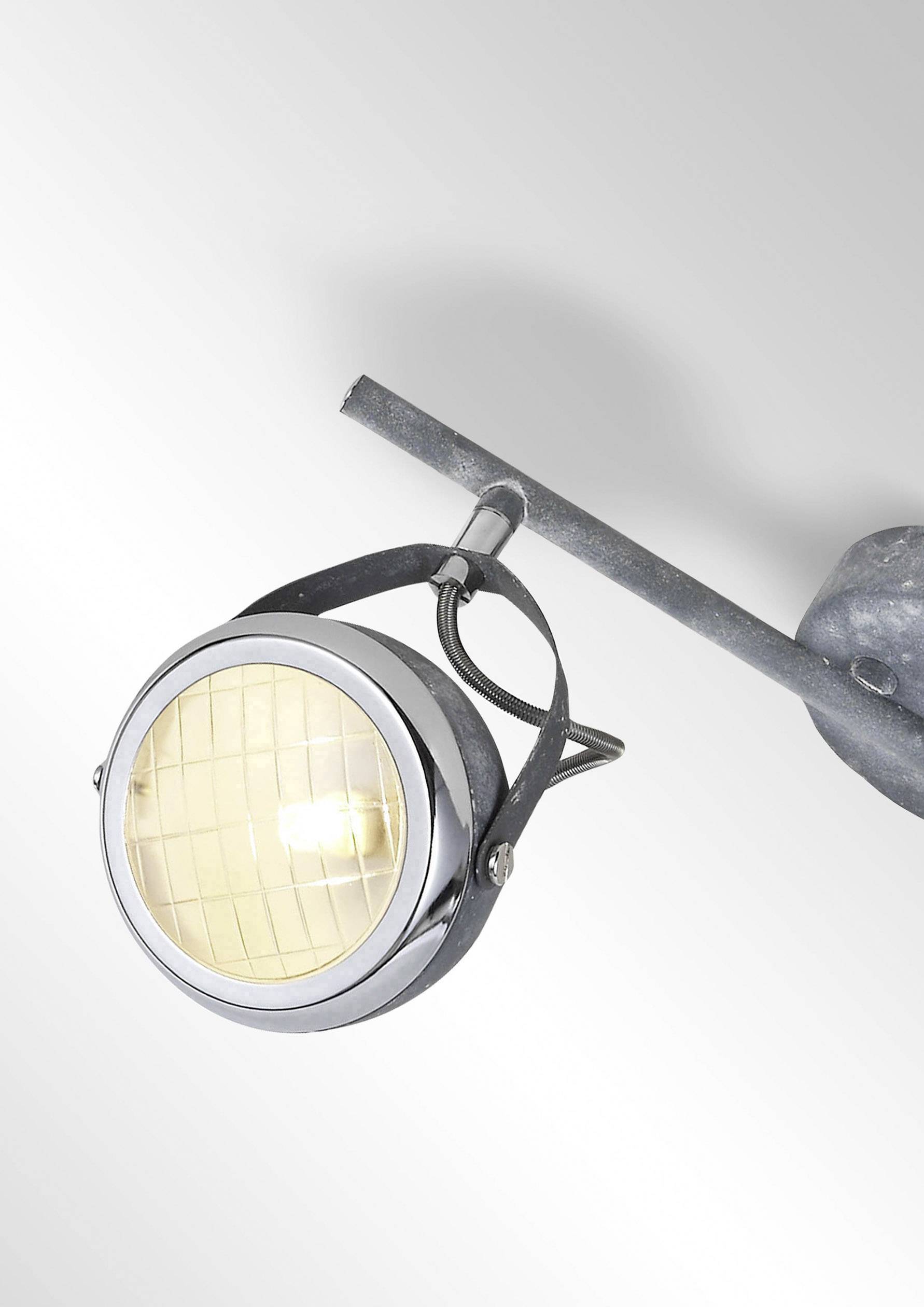Reflektorska lampa s okruglim, rešetkastim sjenilom na okretnoj konzoli, koja emitira toplo svjetlo. Elegantna i moderna.