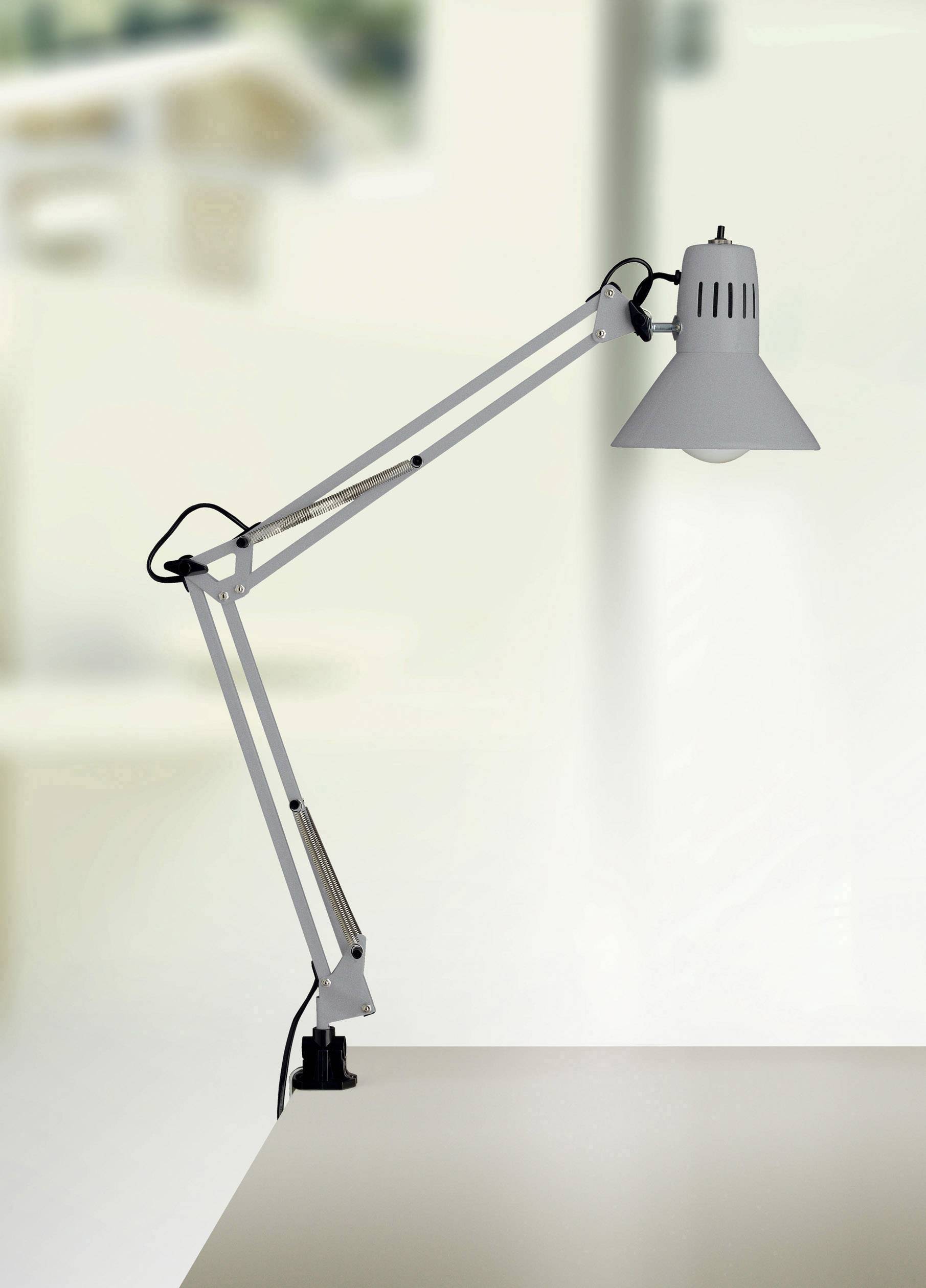 Moderna stolna lampa s podesivom rukom i velikim sjenilom stoji na radnom stolu.